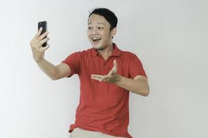 Young Asian man shocked and happy with what he see in the smartphone on isolated grey background. photo