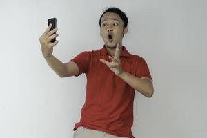 wow, la cara de un joven asiático se sorprendió por lo que vio en el teléfono inteligente con un fondo gris aislado. foto