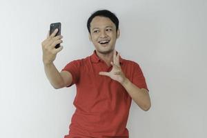 Young Asian man shocked and happy with what he see in the smartphone on isolated grey background. photo