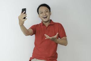 Young Asian man shocked and happy with what he see in the smartphone on isolated grey background. photo