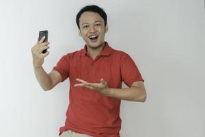 Young Asian man shocked and happy with what he see in the smartphone on isolated grey background. photo