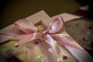 A close up of a pink ribbon on a white chocolate photo