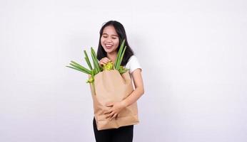 Beautiful asian woman smiling with paper bag of fresh vegetables with isolated white background photo
