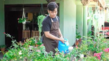 Asian man taking care watering flower at home garden photo