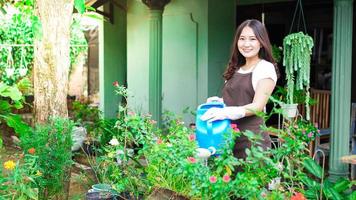 Asian woman taking care watering flower at home garden photo