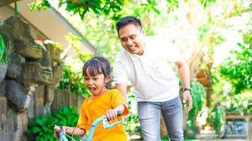 father and daughter practicing bicycles in the park photo