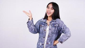 Asian woman smiling wearing jeans jacket and  pointing finger hands up with isolated white background photo