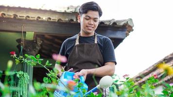 Asian man taking care watering flower at home garden photo