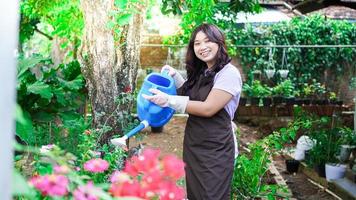 mujer asiática cuidando la flor de riego en el jardín de casa foto