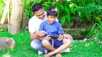 dad and son play games mobile in the park photo