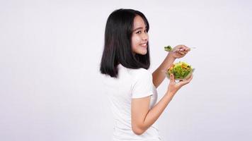 Young asian woman happy eating healthy salad with isolated white background photo