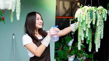 Asian woman taking care watering flower at home garden photo