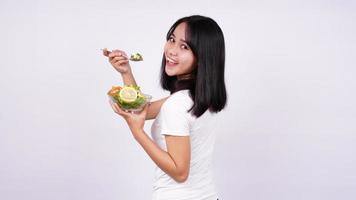 joven mujer asiática feliz comiendo ensalada saludable con fondo blanco aislado foto