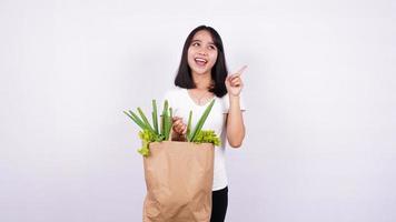 mujer asiática tiene una gran idea con una bolsa de papel de verduras frescas con un fondo blanco aislado