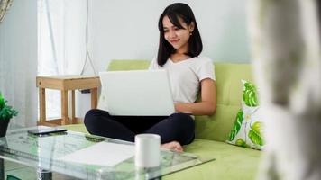 Young beautiful Asian woman working from home using laptop photo