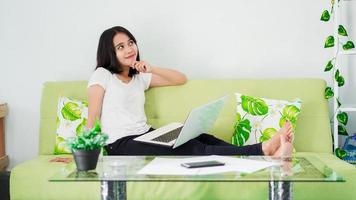 mujeres asiáticas sentadas en una silla trabajando desde casa en una laptop y pensando en la solución del problema foto