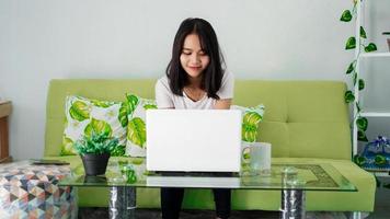 Young beautiful Asian woman working from home using laptop photo