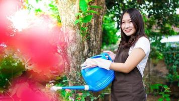 mujer asiática cuidando la flor de riego en el jardín de casa foto