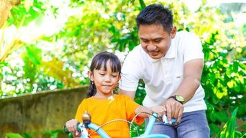 padre e hija jugando bicicletas en el parque foto