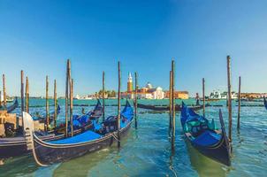 Watercolor drawing of Gondolas moored docked on water in Venice. Gondoliers sailing San Marco basin waterway. San Giorgio Maggiore island