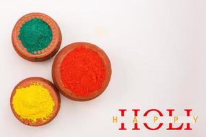 Indian festival Holi concept Multi color's bowl with colorful background and writing happy holi photo