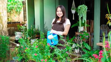 Asian woman taking care watering flower at home garden photo