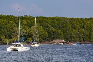 KRABI, THAILAND - JANUARY 22, 2020 - Beautiful natural view of sailboat, boats, pier, mangrove forest and Khao Khanab Nam mountain at Krabi River, Krabi, Thailand. photo