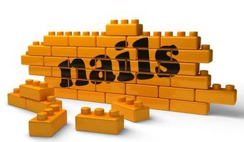 nails word on yellow brick wall photo