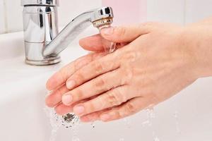 A female washing her hands under warm water
