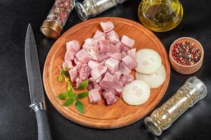 Sliced raw pork meat with spices and a knife on a dark background photo
