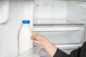 Woman takes out fresh yogurt from fridge photo