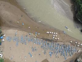 Aerial view of Baron Beach in Gunung Kidul, Indonesia with lighthouse and traditional boat. photo