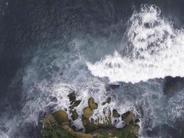 Top down aerial view of giant ocean waves crashing and foaming in coral beach photo