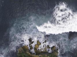 vista aérea de arriba hacia abajo de las olas gigantes del océano rompiendo y haciendo espuma en la playa de coral foto