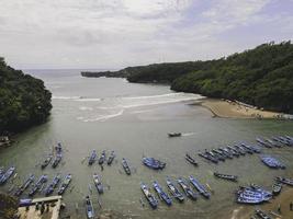 Aerial view of Baron beach in Yogyakarta, Indonesia with lighthouse and traditional boats photo