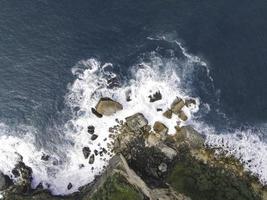 vista aérea de arriba hacia abajo de las olas gigantes del océano rompiendo y haciendo espuma en la playa de coral foto