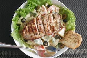 Grilled chicken and fresh vegetable salad on table. photo
