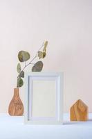 photo frame with eucalyptus branch in wood vase and wood toy on pastel background