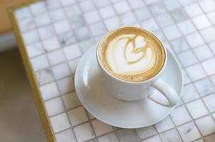 Hot cappuccino with latte art on table photo