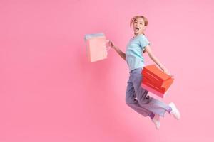 Young Asian woman holding shopping bag on pink background photo