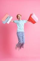 Young Asian woman holding shopping bag on pink background photo