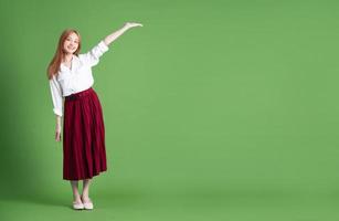 Beautiful young Asian woman dancing and posing on green background photo