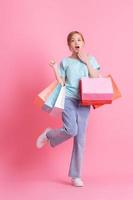 Young Asian woman holding shopping bag on pink background photo