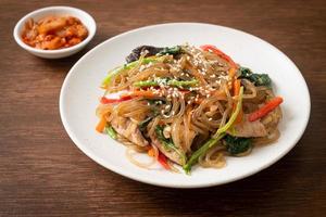 japchae or stir-fried Korean vermicelli noodles with vegetables and pork topped with white sesame photo