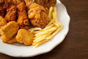 pollo frito con papas fritas y nuggets en un plato foto