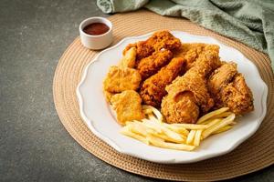 pollo frito con papas fritas y nuggets en un plato foto