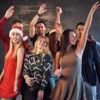 Party with friends. They love Christmas. Group of cheerful young people carrying sparklers and champagne flutes dancing in new year party and looking happy. Concepts about togetherness lifestyle