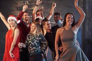 Party with friends. They love Christmas. Group of cheerful young people carrying sparklers and champagne flutes dancing in new year party and looking happy. Concepts about togetherness lifestyle photo