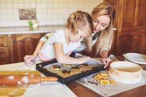 niña feliz con su madre cocinar galletas. foto