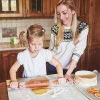 Happy girl with her mother cook cookies. photo